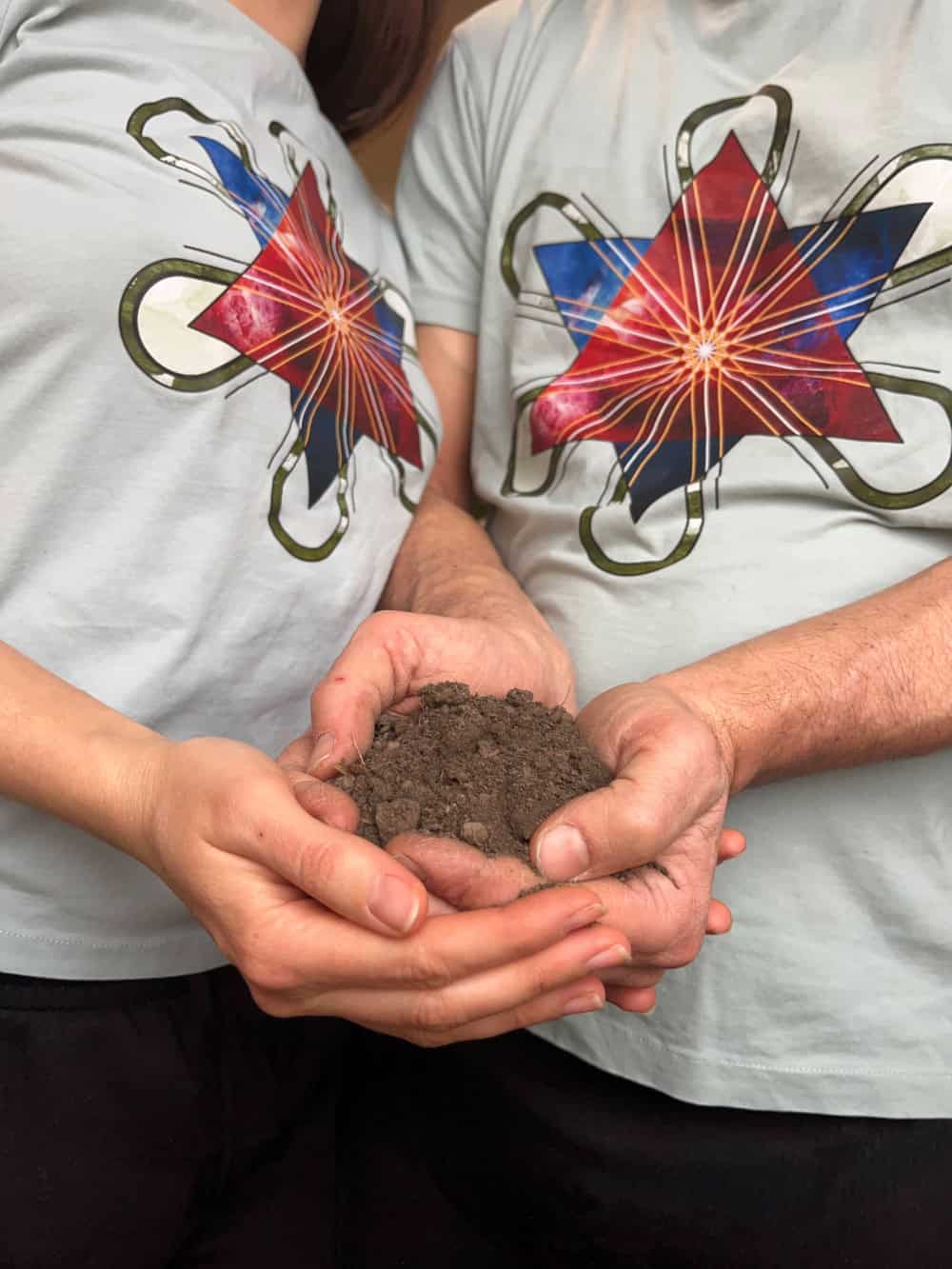 Two people holding a handful of soil, symbolizing gardening and nature.